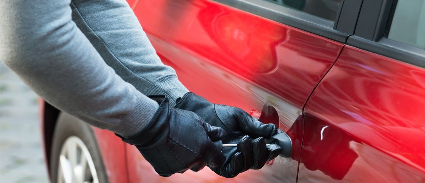 Ratgeber Auto-Diebstahl - Männerhände in Handschuhen versuchen Auto aufzubrechen