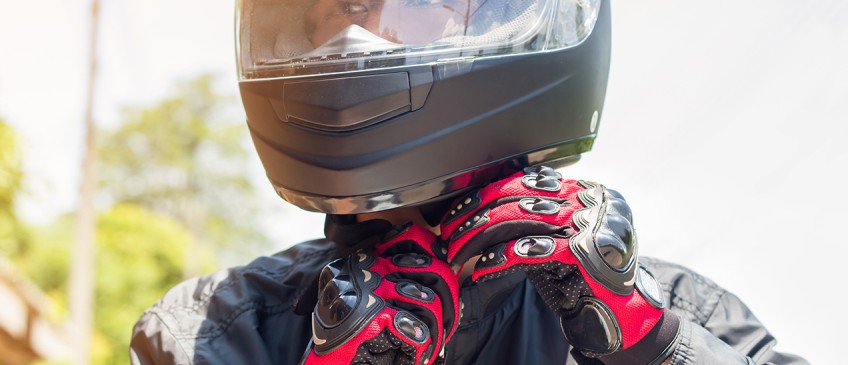 Ratgeber Motorrad - Mensch schließt Motorradhelm am Kopf